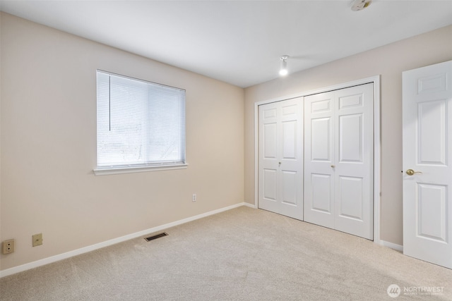 unfurnished bedroom with light carpet and a closet