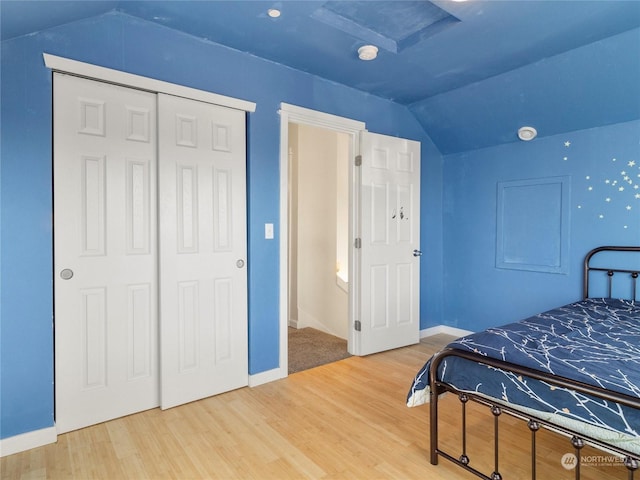 bedroom with lofted ceiling, wood-type flooring, and a closet