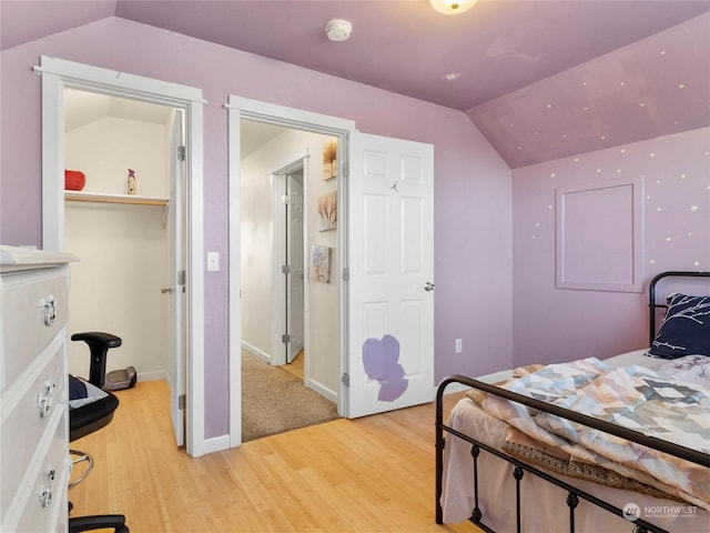 bedroom with vaulted ceiling and light wood-type flooring