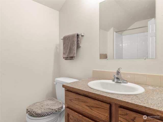 bathroom with lofted ceiling, vanity, toilet, and a shower