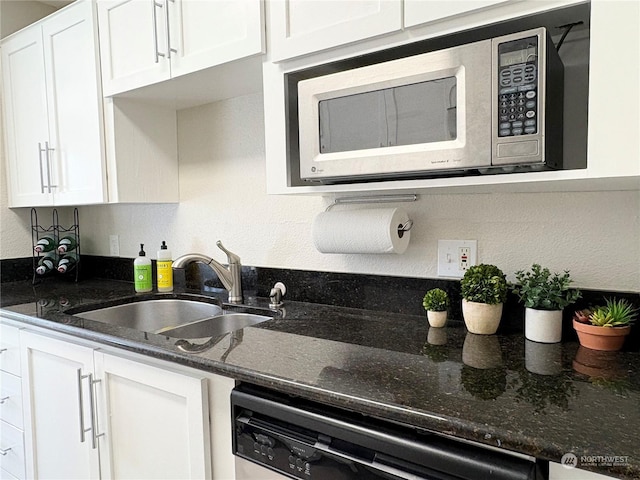 kitchen with white cabinetry, sink, dishwashing machine, and dark stone countertops