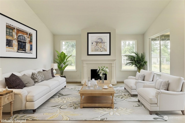 living room featuring vaulted ceiling, a fireplace, and light hardwood / wood-style flooring