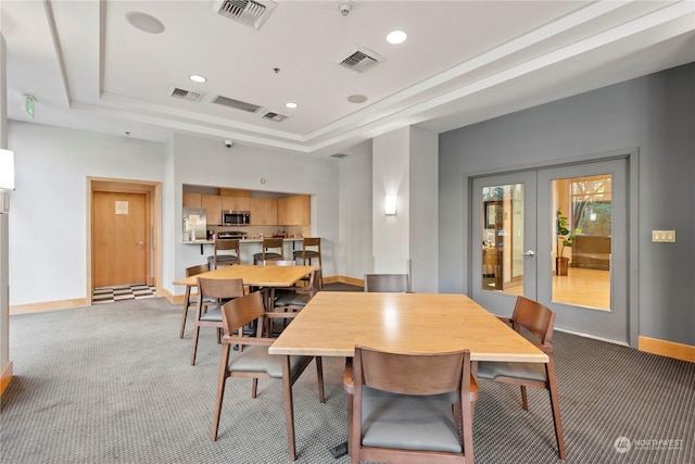 dining room with a tray ceiling, french doors, and carpet