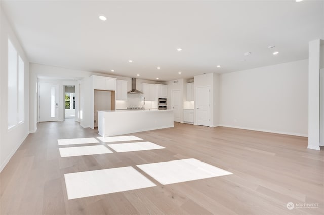 unfurnished living room featuring sink and light hardwood / wood-style floors