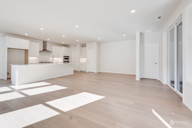 unfurnished living room with sink and light hardwood / wood-style floors