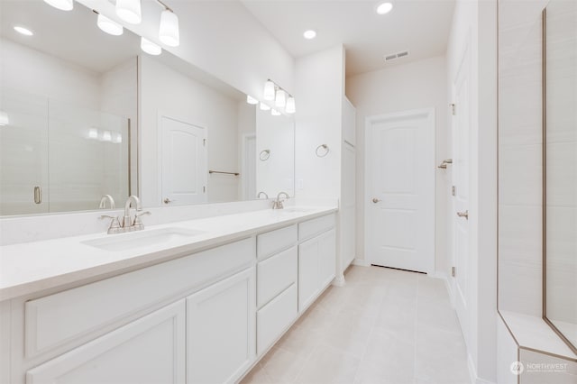 bathroom with a shower with door, vanity, and tile patterned floors