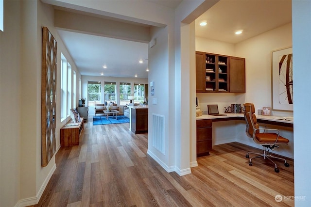 home office with built in desk and light wood-type flooring