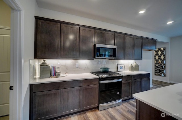 kitchen with decorative backsplash, dark brown cabinets, stainless steel appliances, and light wood-type flooring