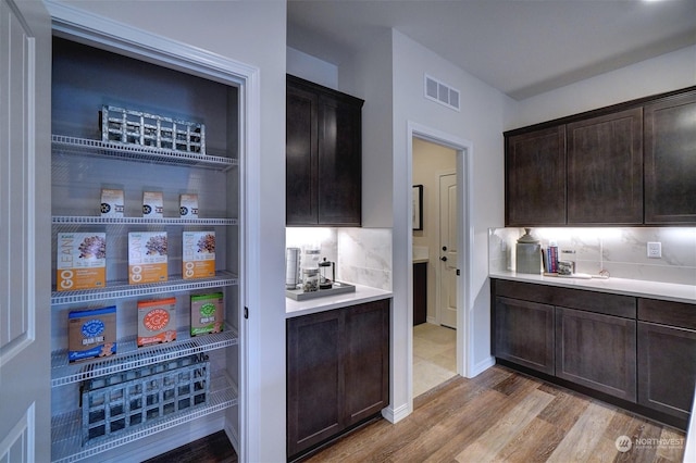 kitchen with hardwood / wood-style flooring, dark brown cabinetry, and backsplash