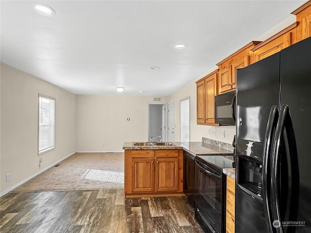 kitchen with sink, dark wood-type flooring, black appliances, and kitchen peninsula