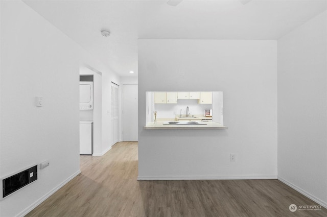 interior space featuring hardwood / wood-style flooring, stacked washing maching and dryer, and sink