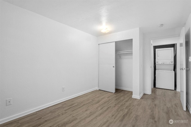 unfurnished bedroom featuring stacked washer / dryer, a closet, and light hardwood / wood-style flooring