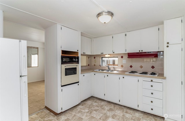 kitchen with sink, backsplash, white appliances, and white cabinetry