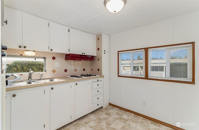 kitchen featuring sink, white cooktop, white cabinets, and tasteful backsplash