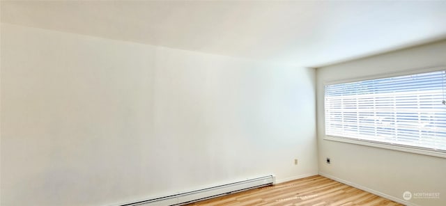 empty room featuring a baseboard radiator and light wood-type flooring