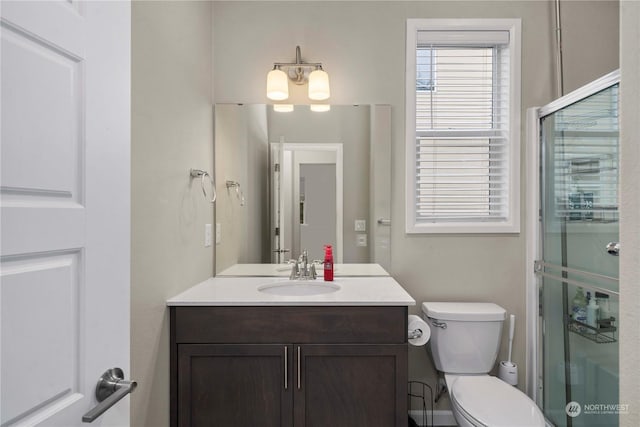 bathroom with vanity, a shower with shower door, and toilet