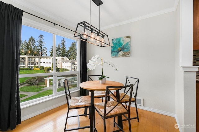 dining space featuring ornamental molding and light hardwood / wood-style flooring