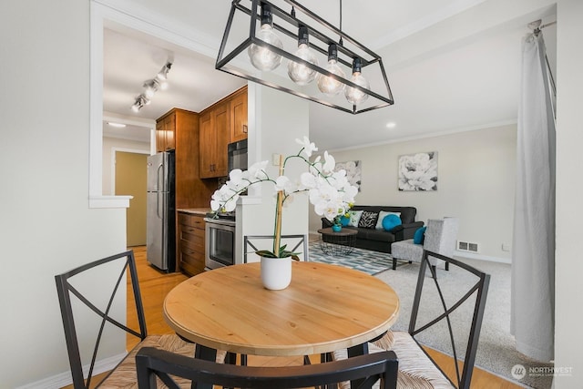 dining area with ornamental molding and rail lighting