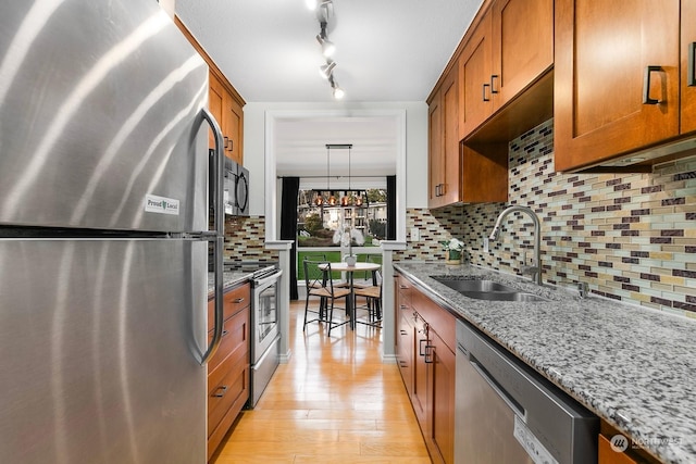 kitchen with light stone countertops, sink, decorative backsplash, and stainless steel appliances