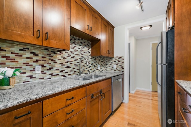 kitchen with sink, light stone counters, backsplash, and appliances with stainless steel finishes