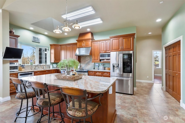 kitchen featuring a breakfast bar, sink, light stone counters, appliances with stainless steel finishes, and a kitchen island