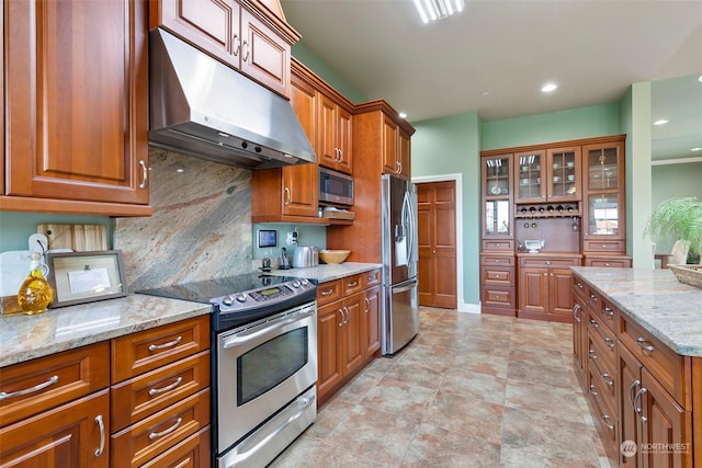 kitchen featuring stainless steel appliances, light stone countertops, and backsplash