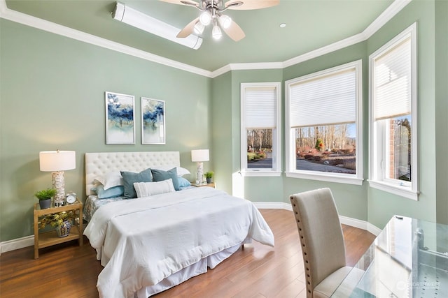 bedroom featuring multiple windows, hardwood / wood-style flooring, ornamental molding, and ceiling fan