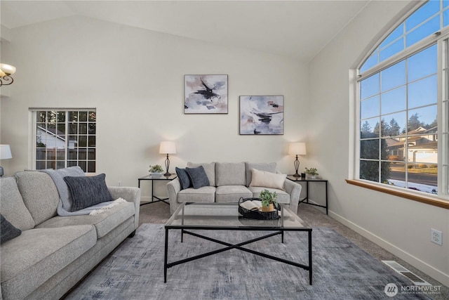 carpeted living room with high vaulted ceiling