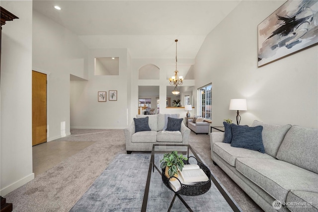 carpeted living room with high vaulted ceiling and a notable chandelier