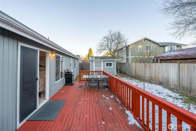 snow covered deck featuring grilling area and a storage shed