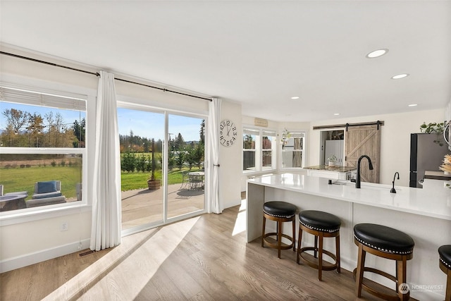 kitchen with a barn door, a breakfast bar, sink, and light wood-type flooring