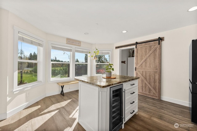 kitchen with white cabinetry, dark hardwood / wood-style floors, a barn door, a kitchen island, and beverage cooler