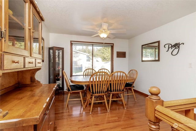 dining space with ceiling fan, a textured ceiling, and light wood-type flooring