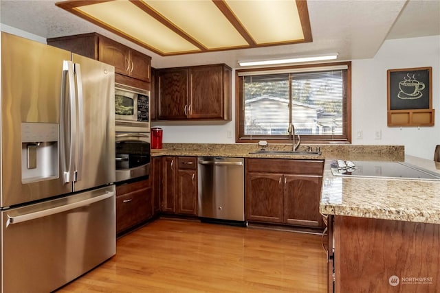 kitchen with appliances with stainless steel finishes, sink, and light wood-type flooring