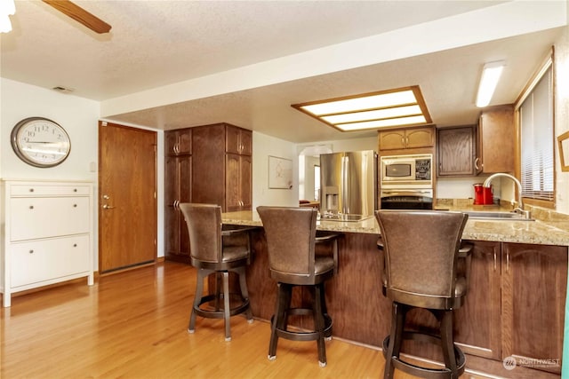 kitchen featuring sink, a kitchen breakfast bar, stainless steel appliances, and light hardwood / wood-style floors