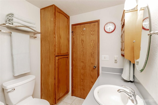 bathroom with toilet, tile patterned flooring, and sink