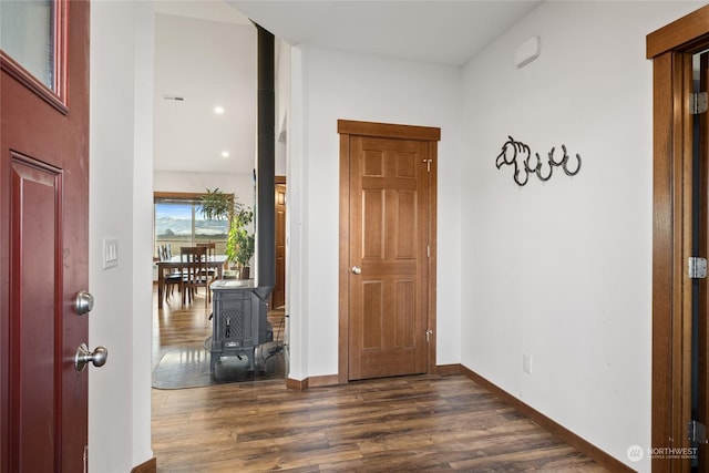 foyer entrance with dark hardwood / wood-style floors and a wood stove