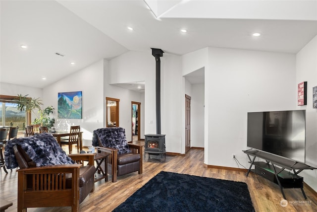 living room with lofted ceiling, light hardwood / wood-style floors, and a wood stove