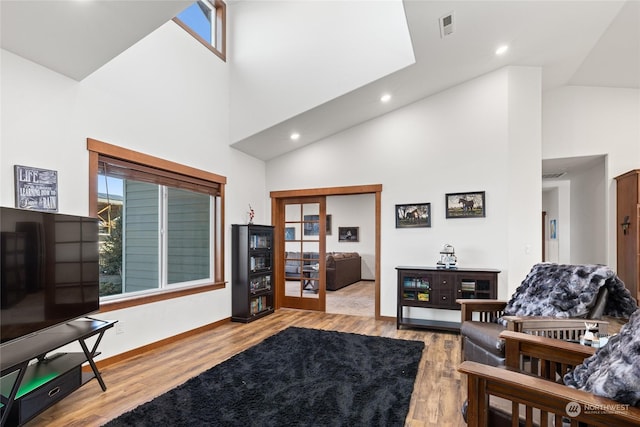 living room with high vaulted ceiling and light wood-type flooring