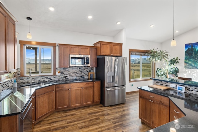 kitchen featuring dark wood-type flooring, sink, hanging light fixtures, appliances with stainless steel finishes, and backsplash