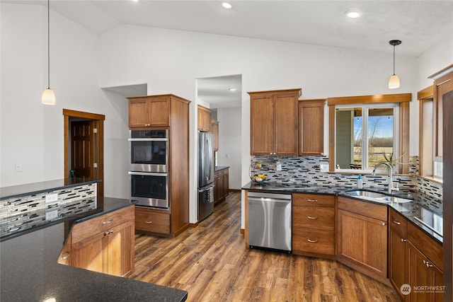 kitchen with pendant lighting, sink, stainless steel appliances, high vaulted ceiling, and tasteful backsplash