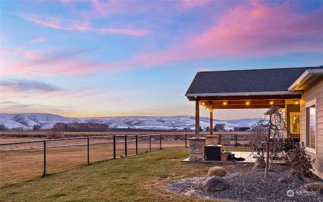 yard at dusk featuring a mountain view and a patio area