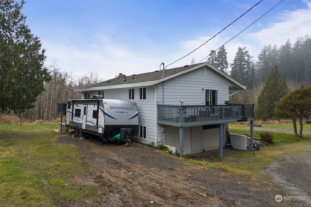 rear view of house with a wooden deck and a lawn