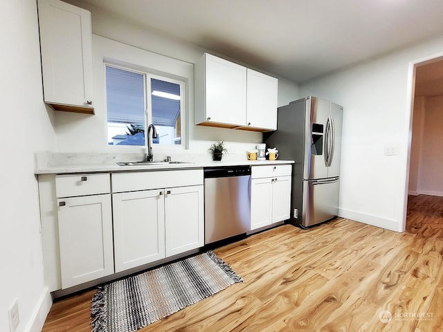 kitchen featuring white cabinetry, sink, light wood-type flooring, and appliances with stainless steel finishes