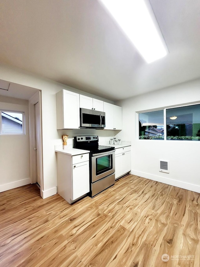 kitchen with white cabinetry, stainless steel appliances, and light hardwood / wood-style flooring