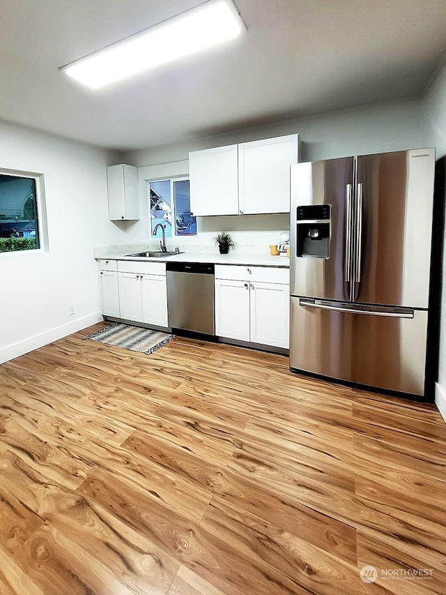 kitchen featuring white cabinetry, sink, stainless steel appliances, and light wood-type flooring