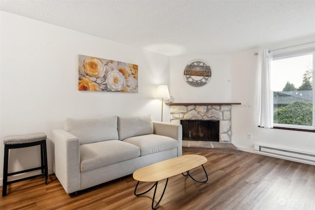 living room with hardwood / wood-style flooring, plenty of natural light, a baseboard heating unit, and a fireplace