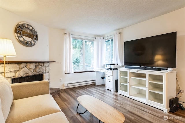 living room featuring a baseboard radiator, a stone fireplace, wood-type flooring, and a textured ceiling