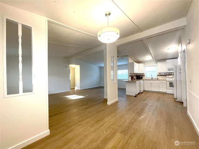 kitchen featuring lofted ceiling, sink, white appliances, white cabinets, and light wood-type flooring