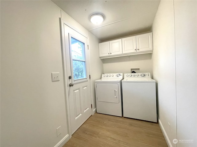 laundry area featuring cabinets, washing machine and dryer, and light wood-type flooring